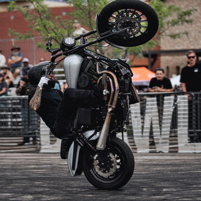 A man performing a handstand on a black motorcycle equipped with TC Bros. 1" Tracker Low Handlebars - Black, Harley models.