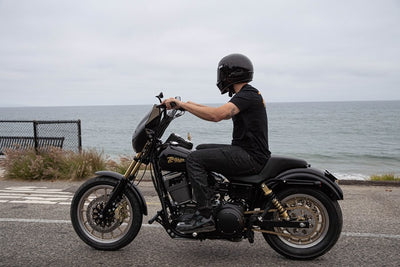 A man is riding a TC Bros. motorcycle near the ocean with ease of installation.