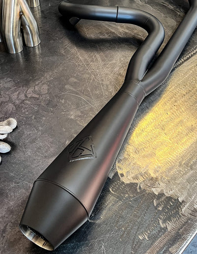 A black SP Concepts Lane Splitter Exhaust M8 Touring FLT 2017-Present is sitting on a table.