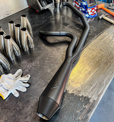 An SP Concepts Big Bore Exhaust M8 Touring FLT 2017-Present (black) is sitting on a table.
