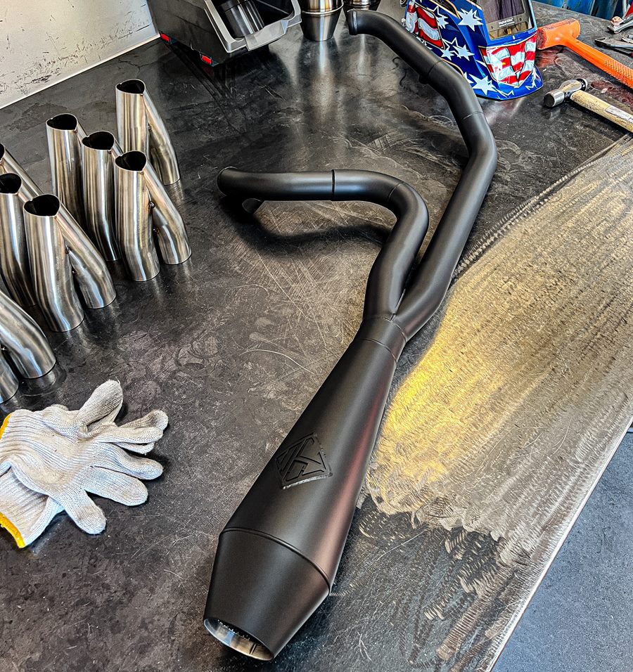 An SP Concepts Big Bore Exhaust M8 Softail 2018-Present (black) is sitting on a table.