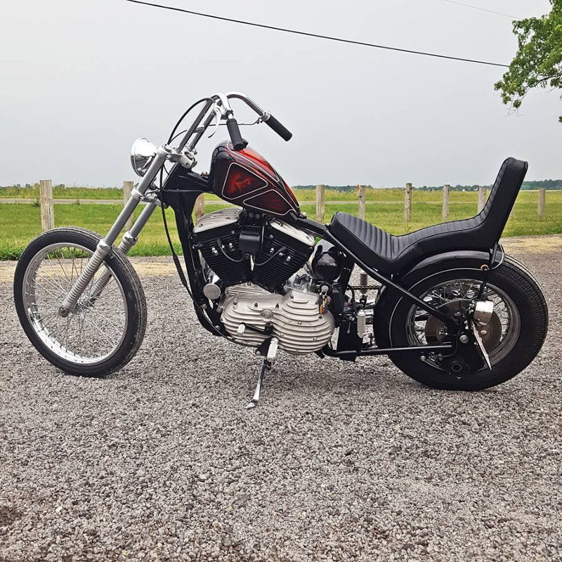 A TC Bros. vintage-style motorcycle with a 6-1/4" Wide Spun Steel Chopper & Bobber Fender by TC Bros Choppers parked on a gravel road.