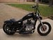 A black Burly Slammer 10.5" Shocks for Harley Davidson Sportster XL 1988-2003 motorcycle parked in front of a house.
