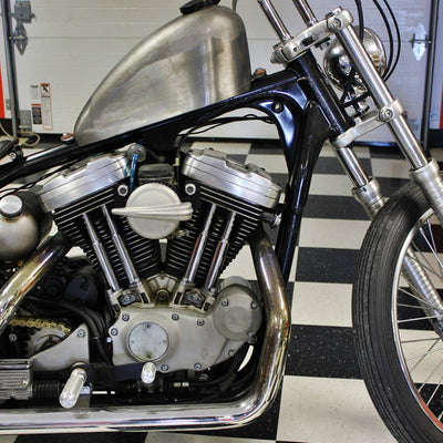 A TC Bros. Streamliner Raw Air Cleaner S&S Super E & G Carbs vintage style motorcycle is parked in a garage.