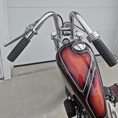 A motorcycle with TC Bros. 1" Single Cable Motorcycle Throttle - Polished handlebars and grips in a vibrant red and orange color.