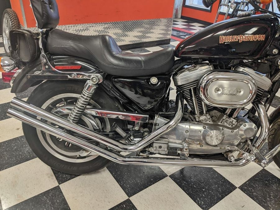 A black Harley Sportster Upsweep Exhaust Pipes for '86-'03 motorcycle is parked in a showroom.