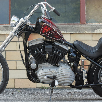 A motorcycle parked in front of a building with Mid-USA Universal 7mm Black Spark Plug Wire Set 28" Long (Fits All Harley Models).