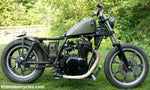 A TC Bros. motorcycle parked in the grass.