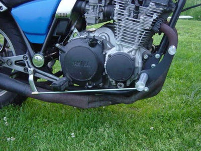 A TC Bros. Yamaha Maxim XJ650 Forward Controls Kit motorcycle, equipped with aftermarket exhausts, is parked in the grass.