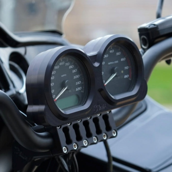 Placed side by side, two billet aluminum components from the TC Bros. Pro Series Gauge Relocation Bezel for Harley Davidson Road Glide feature circular cutouts; one boasts a dark color while the other has a shiny, reflective finish. These bezels from TC Bros. exemplify both style and precision.