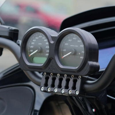 Placed side by side, two billet aluminum components from the TC Bros. Pro Series Gauge Relocation Bezel for Harley Davidson Road Glide feature circular cutouts; one boasts a dark color while the other has a shiny, reflective finish. These bezels from TC Bros. exemplify both style and precision.