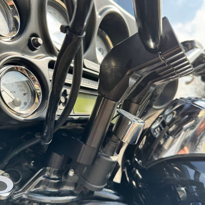 The TC Bros. Pro Series Riser Adapter features black anodized metal, two mounting holes, silver cylindrical ends, and engraved branding—ideal for upgrading 2006-2013 Harley-Davidson Street Glide handlebars.