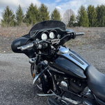 The TC Bros. Pro Series Riser Adapter features black anodized metal, two mounting holes, silver cylindrical ends, and engraved branding—ideal for upgrading 2006-2013 Harley-Davidson Street Glide handlebars.