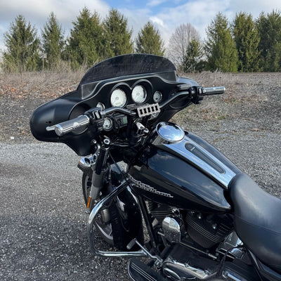 The TC Bros. Pro Series Riser Adapter features black anodized metal, two mounting holes, silver cylindrical ends, and engraved branding—ideal for upgrading 2006-2013 Harley-Davidson Street Glide handlebars.