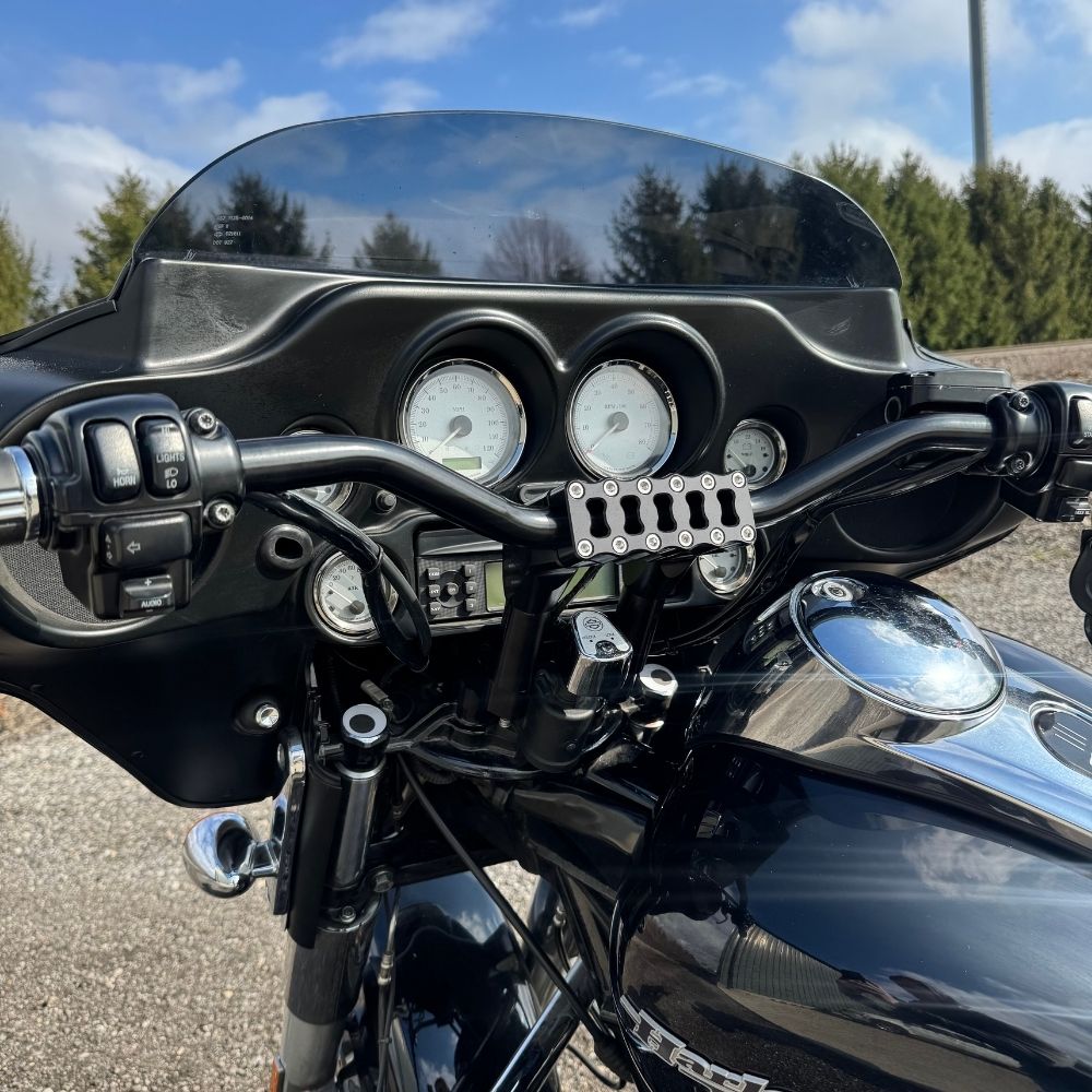 The TC Bros. Pro Series Riser Adapter features black anodized metal, two mounting holes, silver cylindrical ends, and engraved branding—ideal for upgrading 2006-2013 Harley-Davidson Street Glide handlebars.