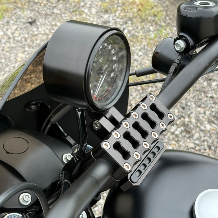 Two cylindrical motorcycle tachometer bezels from TC Bros., including the Pro Series 4 inch Gauge Relocation Bezel for Harley Davidson, in black and silver finishes with similar gauge faces featuring numbers and a red needle.