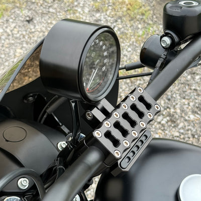 Two cylindrical motorcycle tachometer bezels from TC Bros., including the Pro Series 4 inch Gauge Relocation Bezel for Harley Davidson, in black and silver finishes with similar gauge faces featuring numbers and a red needle.