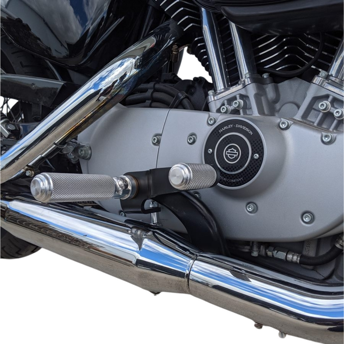 The TC Bros. Nomad Shift/Brake Peg for Harley-Davidson features CNC-machined aluminum pegs in silver, gold, and black with textured grips and threaded bolts. Ideal as a shift or brake peg. "NOMAD SHIFT/TOE PEG" text appears at the top.