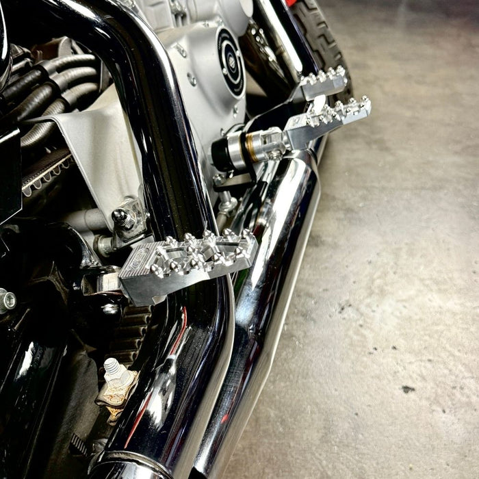 Four TC Bros. Pro Series MX Lite Footpegs for 1977-2022 Harley-Davidson in silver, black, and gold are arranged vertically on a white background.