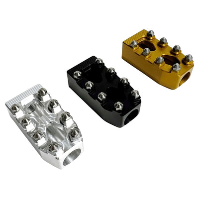 Three TC Bros. Pro Series MX Shifter/Brake Pegs for Harley Davidson, available in silver, black, and gold with multiple spikes, are shown with a metal bolt.