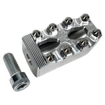 Close-up of a CNC-machined TC Bros. Pro Series MX Shifter/Brake Peg and foot peg assembly, mounted near the engine and exhaust pipes on a concrete surface.