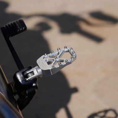 The TC Bros. Pro Series MX Foot Pegs for Harley Davidson come in silver, black, and gold with a rugged, spiked design and diagonal layout for superior grip.