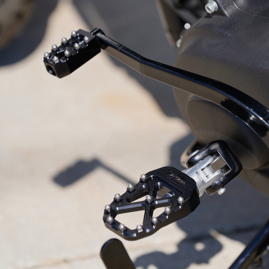 The TC Bros. Pro Series MX Foot Pegs for Harley Davidson come in silver, black, and gold with a rugged, spiked design and diagonal layout for superior grip.