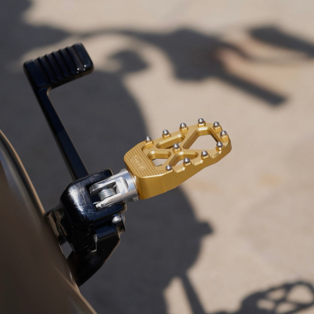 The TC Bros. Pro Series MX Foot Pegs for Harley Davidson come in silver, black, and gold with a rugged, spiked design and diagonal layout for superior grip.