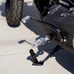 Three TC Bros. Pro Series MX Lite Foot Pegs for Harley Davidson models, featuring metallic spiked surfaces, are arranged side by side in silver, black, and gold.