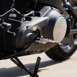 Three TC Bros. Pro Series MX Lite Foot Pegs for Harley Davidson models, featuring metallic spiked surfaces, are arranged side by side in silver, black, and gold.