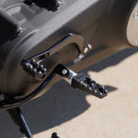 Three TC Bros. Pro Series MX Lite Foot Pegs for Harley Davidson models, featuring metallic spiked surfaces, are arranged side by side in silver, black, and gold.