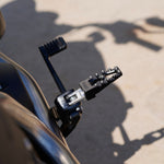 Three TC Bros. Pro Series MX Lite Foot Pegs for Harley Davidson models, featuring metallic spiked surfaces, are arranged side by side in silver, black, and gold.