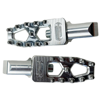 Two silver metal TC Bros. Pro Series MX Lite Passenger Foot Pegs for 2018-newer Harley Softail & Pan America with a durable and rugged design, featuring notched edges for grip and an open frame structure, showcased against a plain background. These high-performance foot pegs are perfect for Harley Softail riders seeking both style and functionality.