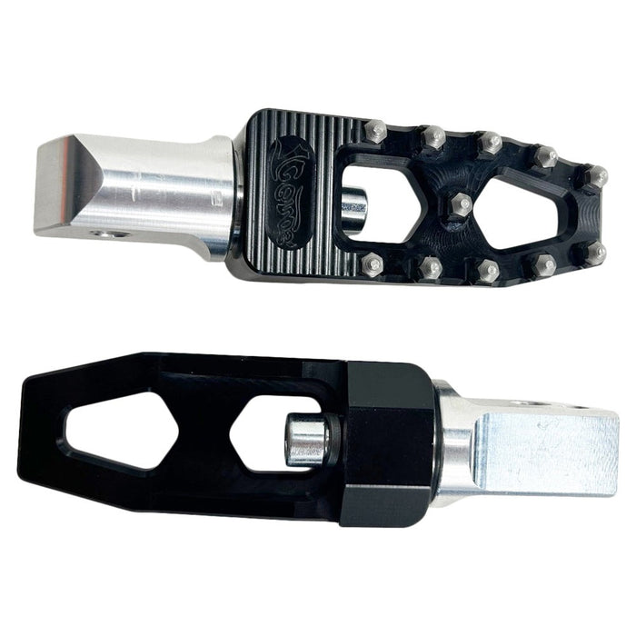 Two TC Bros. Pro Series Black MX Lite Passenger Foot Pegs for 2018-newer Harley Softail & Pan America with black, spiked foot platforms and silver attachment points, reminiscent of high performance motorcycle foot pegs, displayed side by side against a white background.