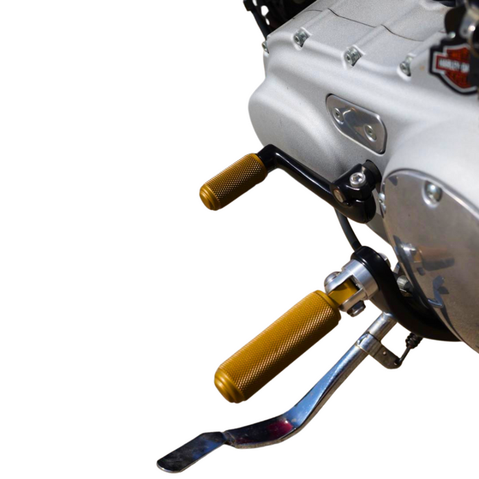 The TC Bros. Nomad Shift/Brake Peg for Harley-Davidson features CNC-machined aluminum pegs in silver, gold, and black with textured grips and threaded bolts. Ideal as a shift or brake peg. "NOMAD SHIFT/TOE PEG" text appears at the top.