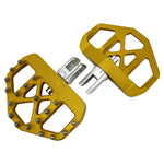 Three TC Bros. Pro Series MX Mini Floorboards for Harley-Davidson, in silver, black, and gold, are diagonally arranged on a white background.