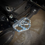 Three TC Bros. Pro Series MX Mini Floorboards for Harley-Davidson, in silver, black, and gold, are diagonally arranged on a white background.