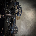 Three TC Bros. Pro Series MX Mini Floorboards for Harley-Davidson, in silver, black, and gold, are diagonally arranged on a white background.