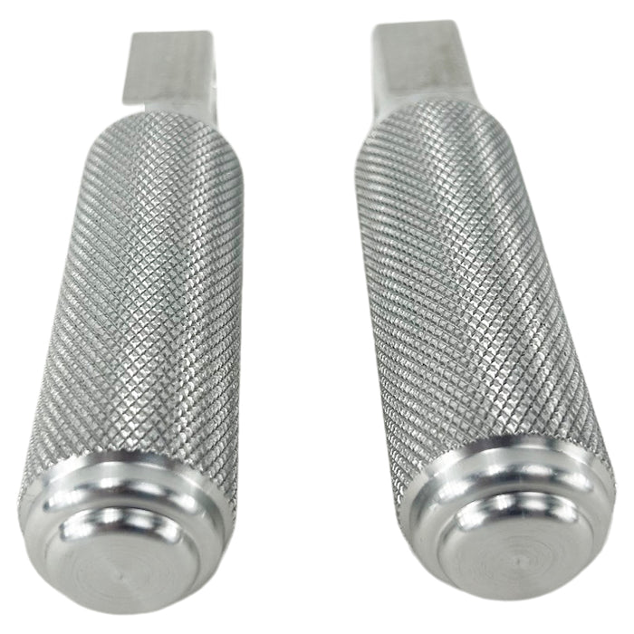 Two stainless steel TC Bros. Nomad Passenger Foot Pegs fits 2018-up Harley Softail M8 & Pan America, one upright and one lying on its side, showcasing their textured grip surfaces and mounting holes—perfect for adding a touch of rugged functionality.