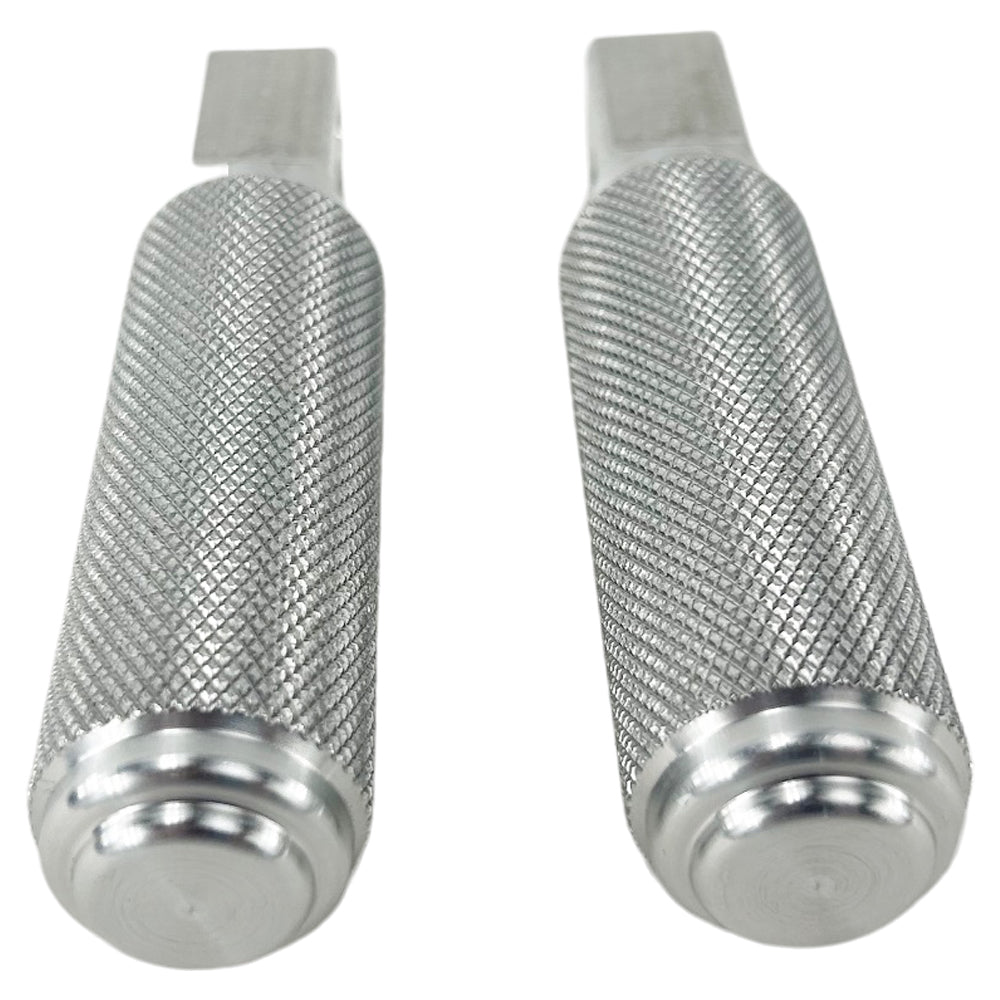 Two stainless steel TC Bros. Nomad Passenger Foot Pegs fits 2018-up Harley Softail M8 & Pan America, one upright and one lying on its side, showcasing their textured grip surfaces and mounting holes—perfect for adding a touch of rugged functionality.