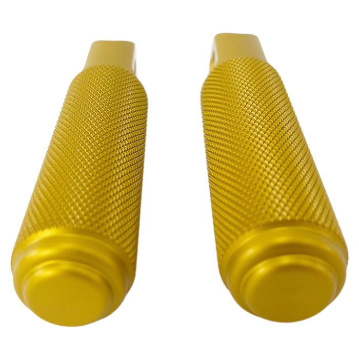 Two gold-tone metal cylindrical objects with textured grips, featuring a hole through their flat end pieces, arranged in a straight line. Crafted from CNC machined aluminum, these resemble TC Bros Nomad Passenger Foot Pegs fits 2018-up Harley Softail M8 & Pan America - Gold.