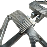 Close-up of TC Bros. Pro Series MX Slim Floorboards for 1984-Up Harley-Davidson Touring, featuring CNC-machined billet aluminum and visible bolts, mounted on a black Harley-Davidson motorcycle on a concrete floor.