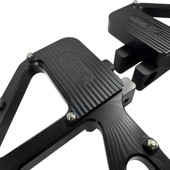 TC Bros. Pro Series MX Slim Floorboards for Harley Davidson Bagger Touring Models feature a skeletal design with metal pins, resembling high-performance pedals in silver, black, and gold. Arranged diagonally, they offer a striking visual appeal.