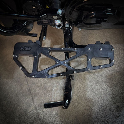 TC Bros. Pro Series MX Slim Floorboards for Harley Davidson Bagger Touring Models feature a skeletal design with metal pins, resembling high-performance pedals in silver, black, and gold. Arranged diagonally, they offer a striking visual appeal.