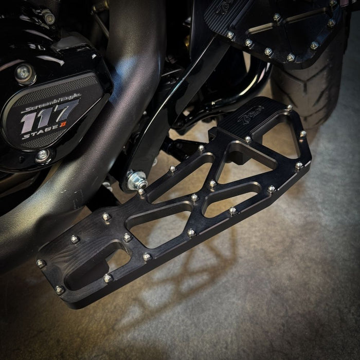 TC Bros. Pro Series MX Slim Floorboards for Harley Davidson Bagger Touring Models feature a skeletal design with metal pins, resembling high-performance pedals in silver, black, and gold. Arranged diagonally, they offer a striking visual appeal.