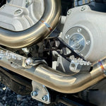 Two TC Bros. Pro Series Truss Brake Pedals, crafted from billet aluminum—one in silver and the other in black—feature geometric cutout designs inspired by a truss brake arm and secure hex bolt attachments, arranged diagonally on a white background; designed specifically for 1999-2017 Harley-Davidson Dyna models.