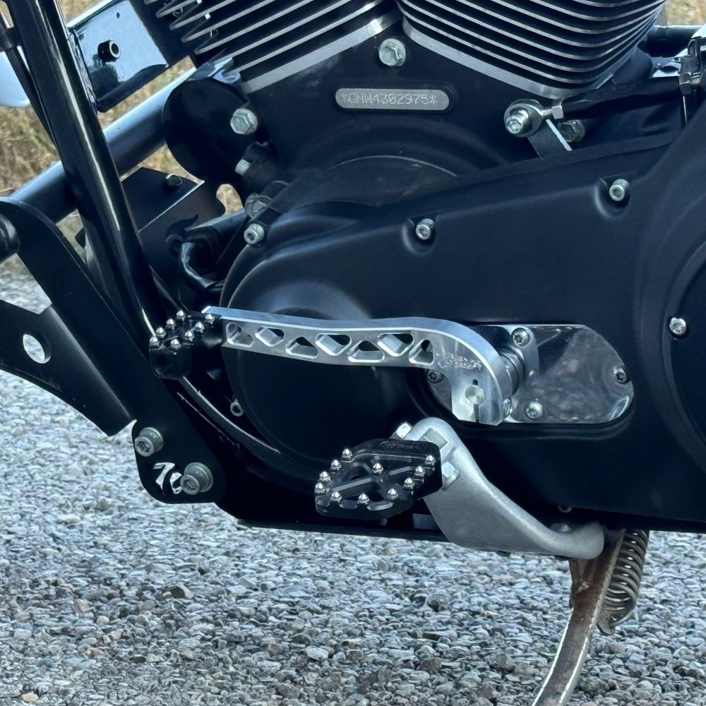 Two billet aluminum TC Bros. Pro Series Truss Shift Levers for 1991-2017 Harley-Davidson Dyna, one black and one silver, with cutout geometric patterns, are displayed on a white background—perfect for your next CNC machined upgrade.