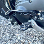 Two billet aluminum TC Bros. Pro Series Truss Shift Levers for 1991-2017 Harley-Davidson Dyna, one black and one silver, with cutout geometric patterns, are displayed on a white background—perfect for your next CNC machined upgrade.
