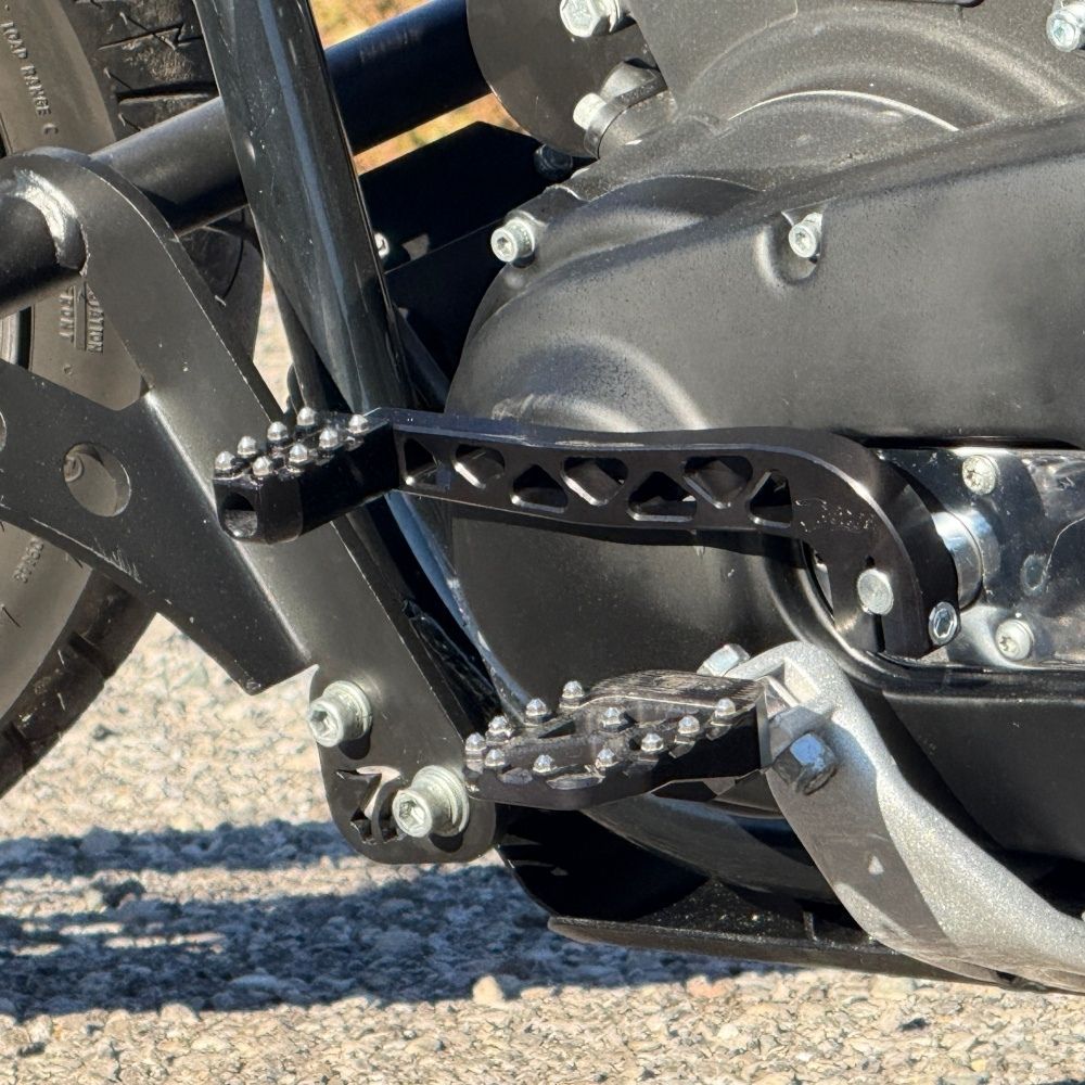 Two billet aluminum TC Bros. Pro Series Truss Shift Levers for 1991-2017 Harley-Davidson Dyna, one black and one silver, with cutout geometric patterns, are displayed on a white background—perfect for your next CNC machined upgrade.