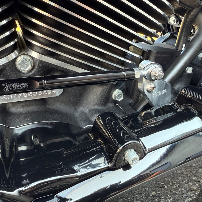 Two metal brackets, one silver and one black, each with a matching screw and bolt, displayed on a white background. Text reads "TC Bros. Pro Series Easy Shift Lever Extension for Harley-Davidson Big Twin—Milwaukee-Eight.